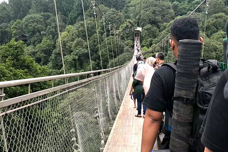 Wisatawan melintasi Suspesion Bridge yang terletak di kawasan wisata Situ Gunung, Sukabumi, Jawa Barat, Minggu (13/1/2019).
