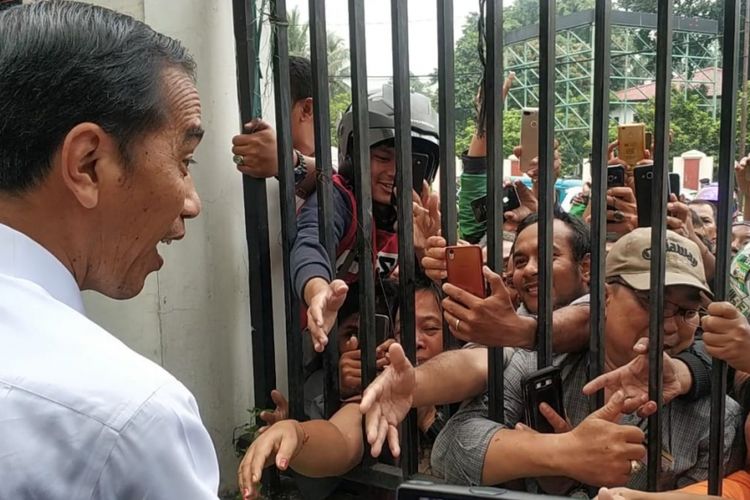 Presiden Joko Widodo (Jokowi) bersalaman dengan warga yang menunggunya di luar pagar GOR Pasar Minggu, Jakarta Selatan, Jumat (22/2/2019).