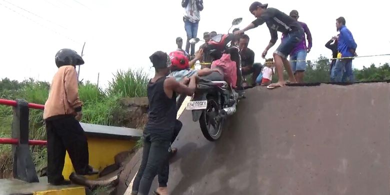 Akibat banjir yang memutuskan Jembatan Sungai Rungau di Jalan Trans Kalimantan, Kabupaten Seruyan, Kalimantan Tengah, warga harus menggotong sepeda motornya untuk melintass