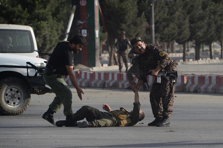 Tentara keamanan Afghanistan berusaha membentu rekannya yang terluka akibat serangan bom bunuh diri di Bandara Internasional Kabul, pada Minggu (22/7/2018).