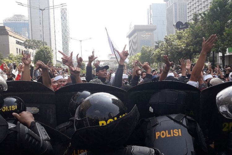 Massa peserta aksi 22 Mei menyanyikan yel-yel sambil mengacungkan dua jari di depan Djakarta Theatre, Rabu (22/5/2019).