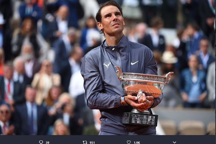 Petenis Spanyol, Rafael Nadal, menggenggam trofi French Open 2019 yang diraih setelah mengalahkan Dominic Thiem dalam laga final, Minggu (9/6/2019).