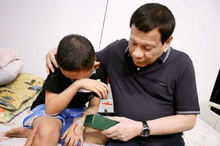 Presiden Filipina Rodrigo Duterte saat memberi hadiah kepada salah seorang anak penderita kanker di rumah sakit di Davao, Minggu (23/12/2018).