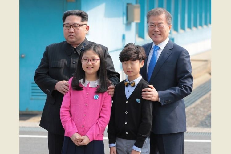 Pemimpin Korea Utara Kim Jong Un (kiri) dan Presiden Korea Selatan Moon Jae-in (kanan) berpose bersama anak-anak, saat bertemu di Garis Demarkasi Militer yang membagi negara mereka menjelang pertemuan puncak di Panmunjom, Jumat (27/4/2018). (AFP/Korea Summit Press Pool)