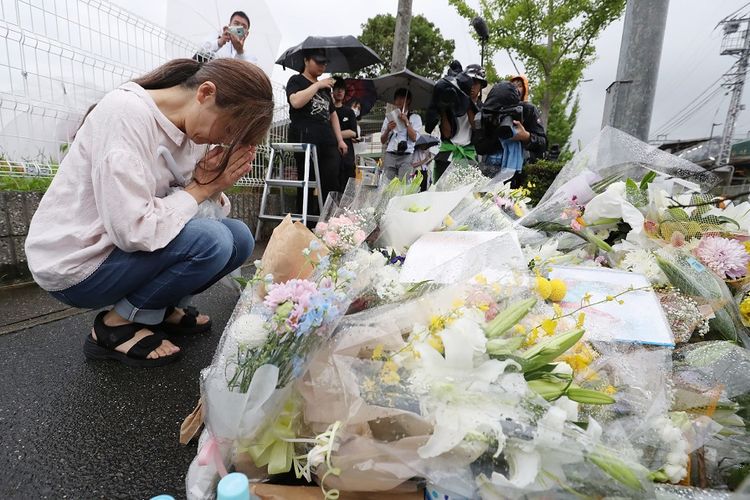 Seorang warga berdoa di depan tumpukan karangan bunga yang ditujukan bagi para korban meninggal dalam kasus pembakaran studio animasi, Kyoto Animation, di Kyoto, pada Kamis (18/7/2019) lalu.