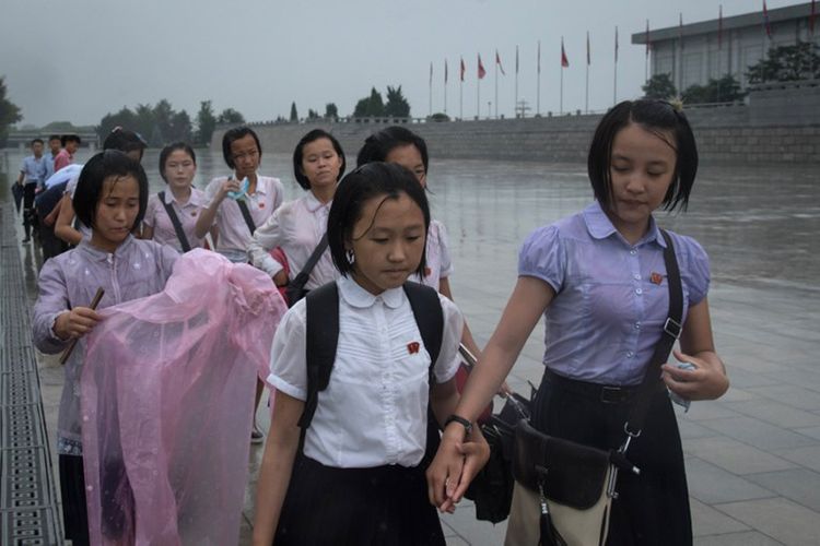 Para pelajar di Pyongyang, Korea Utara berjalan menembus hujan untuk memberikan penghormatan kepada kepada pemimpian Korut Kim Il-Sung dan Kim Jong-Il di luar Istana Kumsusan. Ritual ini mereka lakukan dalam rangka memperingati Hari Kemenangan  yang jatuh setiap tanggal 27 Juli.  