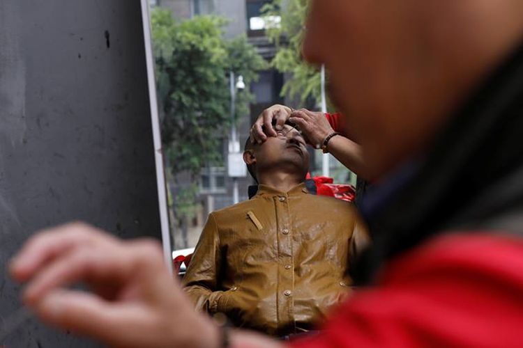 Seorang pelanggan dari Xiong Gaowu, pria 62 tahun yang menjalankan praktik pangkas kelopak mata di pinggir jalan Kota Chengdu, Provinsi Sichuan, China. Foto ini diambil pada 18 November 2017.  