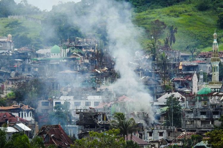 Asap mengudara dari bangunan-bangunan yang terbakar sebagai dampak dari pertempuran antara pasukan pemerintah Filipina dan gerombolan teroris di Kota Marawi. Pemandangan ini diabadikan pada 3 Juli 2017.  