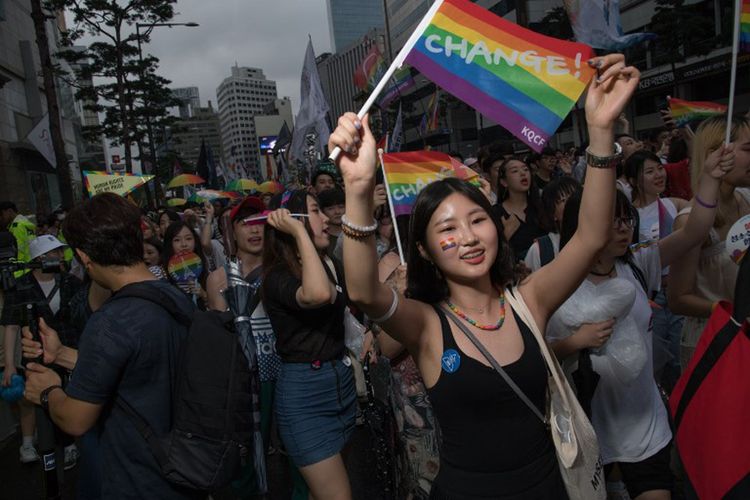 Seorang peserta aksi untuk hak kaum lesbian, gay, biseksual, dan transgender (LGBT) di Kota Seoul. Korea Selatan, Sabtu (15/7/2017), mengibarkan bendera pelangi.  Ribuan orang ambil bagian dalam aksi ini dengan bernyanyi, dan menari, tanpa peduli dengan hujan dan protes kelompok Kristen konservatif.  