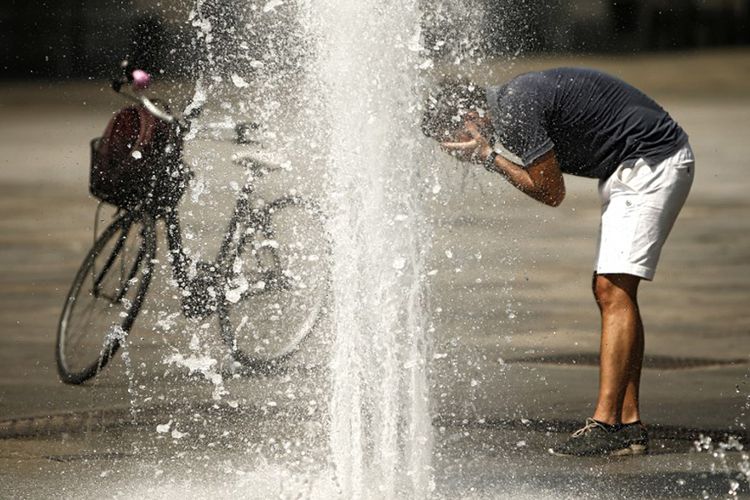 Seorang pria mendinginkan dirinya di air mancur Piazza Castello di Turin (2/8/2017)