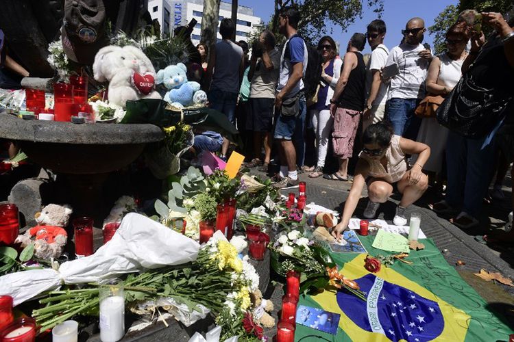 Seorang wanita meletakkan sesuatu di dekat karangan bunga, pesan-pesan, dan sejumlah mainan anak yang dipasang untuk mengenang serangan di Kota Cambrils, Spanyol pada Jumat (18/8/2017).  