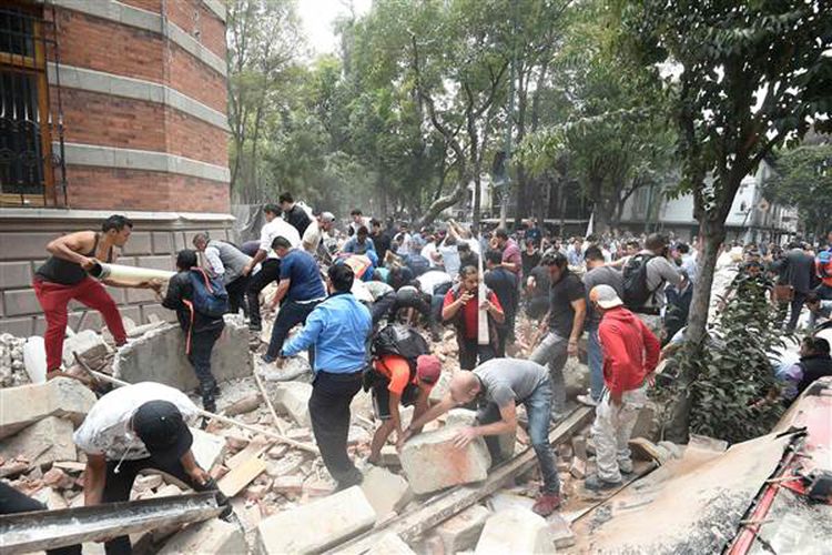 Orang-orang mengangkat puing-puing bangunan yang rusak setelah gempa mengguncang Mexico City pada 19 September 2017.