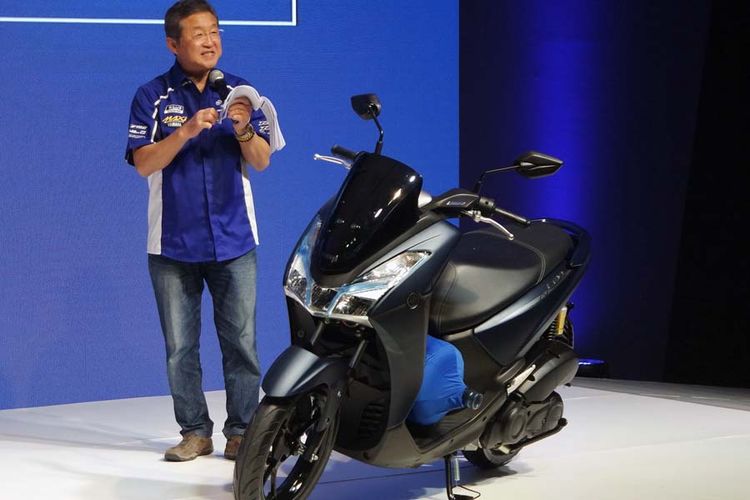 Presiden Direktur Yamaha Indonesia Motor Manufacturing Minoru Morimoto mempraktekan ruang kaki Yamaha Lexi 125 muat botol galon minuman.