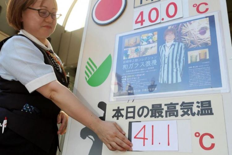 Karyawan sebuah departement store di Kumagaya memasang angka yang menunjukkan suhu udara kota itu pada Senin (23/7/2018).