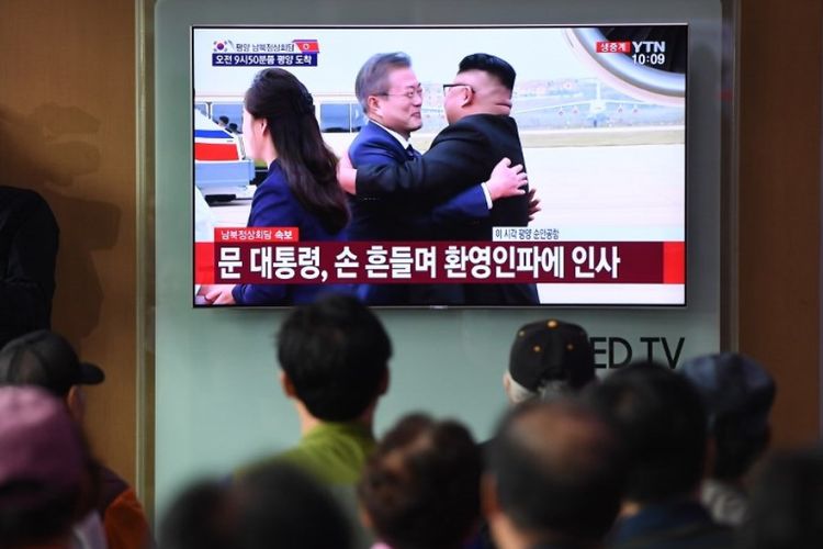 Warga Seoul di stasiun kereta api menyaksikan pada layar kaca momen Presiden Korea Selatan Moon Jae-in tiba di bandara Pyongyang dan disambut oleh pemimpin Korea Utara Kim Jong Un. (AFP/Jung Yeon-je)