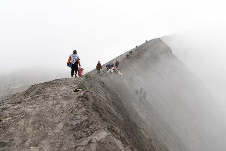 Masyarakat suku Tengger melintas di bibir kawah Gunung Bromo untuk melarung sesajen pada Upacara Yadnya Kasada, Probolinggo, Jawa Timur, Kamis (18/7/2019). Upacara Kasada merupakan upacara adat masyarakat Suku Tengger sebagai bentuk ucapan syukur kepada Sang Hyang Widi sekaligus meminta berkah dan menjauhkan dari malapetaka.