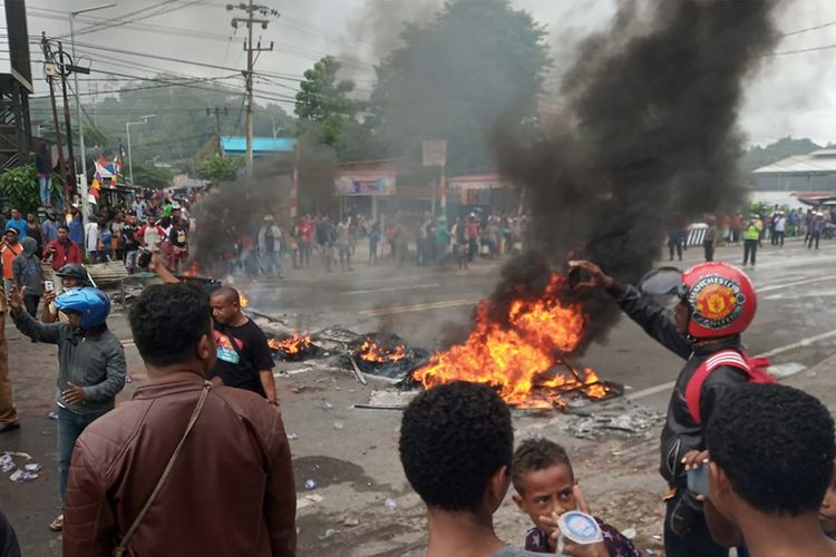 Massa membakar ban saat kerusuhan di pintu masuk Jalan Trikora Wosi Manokwari, Senin (19/8/2019).  Aksi ini merupakan buntut dari kemarahan mereka atas peristiwa yang dialami mahasiswa asal Papua di Surabaya, Malang dan Semarang.