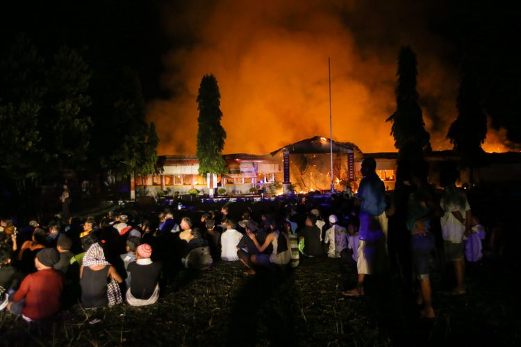 Narapidana dan tahanan dikumpulkan di halaman saat terjadi kebakaran di Rumah Tahanan Donggala, Sulawesi Tengah, Minggu (30/9/2018) pasca kerusuhan tahanan. Kerusuhan dipicu permintaan narapidana dan tahanan dibebaskan untuk menemui keluarga yang terkena musibah gempa tidak dipenuhi. Sekitar 100 tahanan dikabarkan melarikan diri.