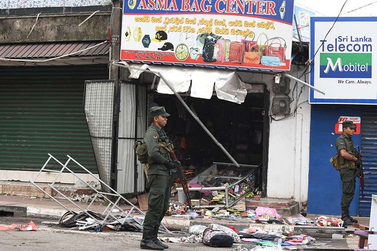 Aparat keamanan berjaga di dekat bangunan toko yang rusak akibat serangan yang dilakukan sebuah kelompok massa di Minuwangoda, Sri Lanka, Selasa (14/5/2019). Satu orang dilaporkan tewas dalam aksi kerusuhan anti-Muslim di Sri Lanka pada Senin, 13 Mei lalu, hingga diberlakukannya jam malam secara nasional.