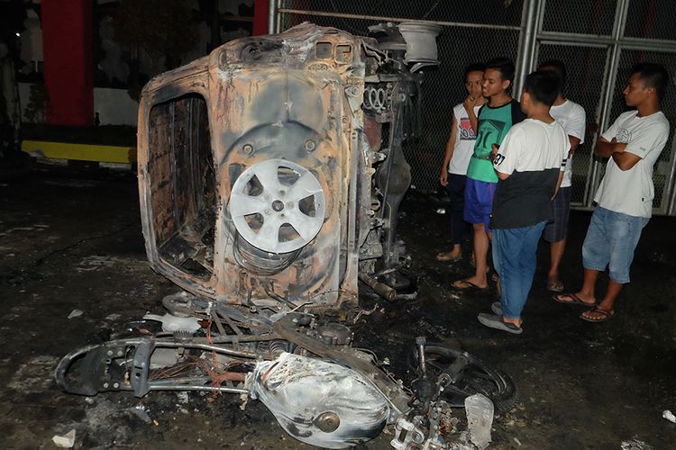 Warga melihat bangkai mobil yang rusak dampak kerusuhan di Lapas Narkotika Kelas III Langkat, di Langkat, Sumatera Utara, Kamis (16/5/2019). Akibat peristiwa kerusuhan yang dilakukan para narapidana di Lapas tersebut mengakibatkan tiga mobil dan dua sepeda motor petugas rusak terbakar dan ratusan napi melarikan diri.