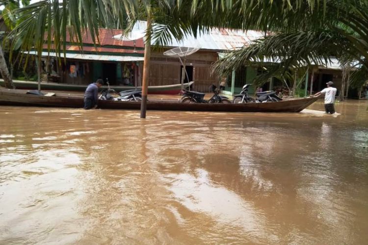 Warga menggunakan perahu untuk melewati jalan utama yang terendam banjir di Desa Suka Maju, Kecamatan Sultan Daulat, Kota Subulussalam, Aceh, Jumat (14/12/2018)