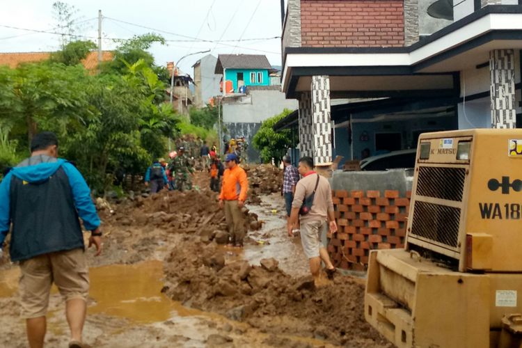 Tampak petugas gabungan dari sejumlah instansi membantu membersihkan material lumpur dan batuan yang terbawa banjir bandang yang disebabkan tanggul penahan aliran air sungai di sekitar Komplek Jatiendah Regency jebol diterjang. 