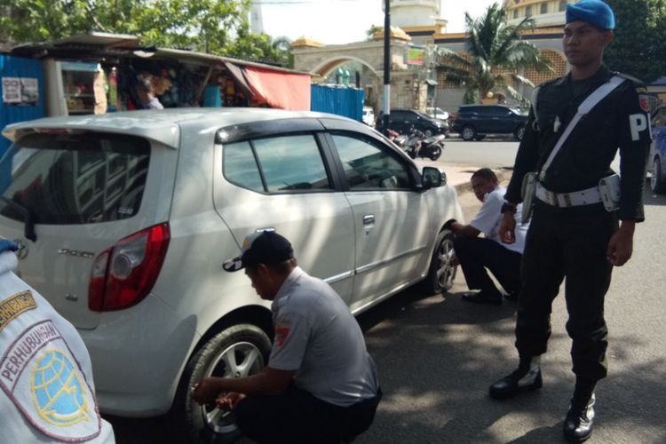 Sejumlah petugas Dinas Perhubungan Kota Ambon mengempiskan sebuah mobil yang parkir sembarangan di kawasan jalan Sam Ratulangi Ambon, Sabtu (10/2/2018).