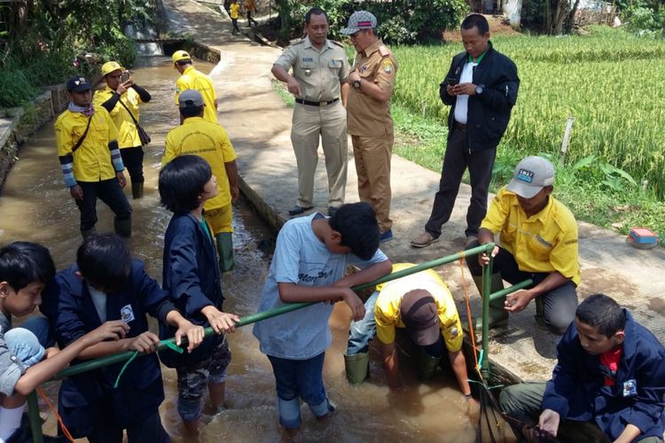 Pelajar Internasional Green School bersama tim URC DLHK Sumedang memasang jaring penahan sampah untuk mengatasi masalah banjir yang kerap merendam Jalan Kutamaya, Kompleks Islamic Center Sumedang, Selasa (26/2/2019). 