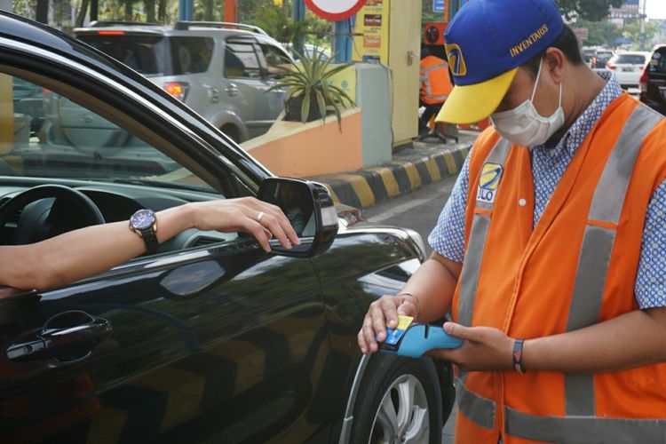 Petugas Tol sedang membantu pengemudi melakukan pembayaran melalui alat mobile reader.