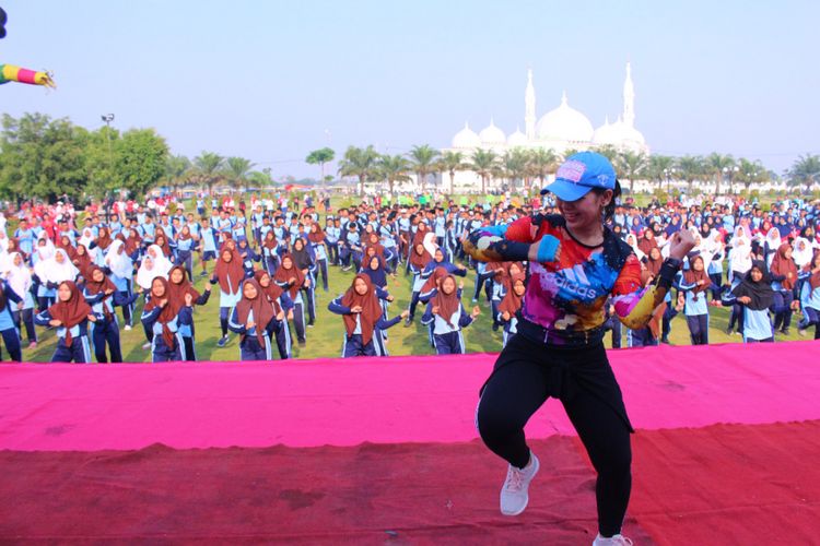 GOYANG DAYUNG --Nampak instruktur senam memimpin senam goyang dayung yang dipopulerkan Presiden Jokowi saat pembukaan Asean Games 2018 di Alun - alun Rekso Gati, Mejayan, Kabupaten Madiun, Jumat (21/9/2018).
