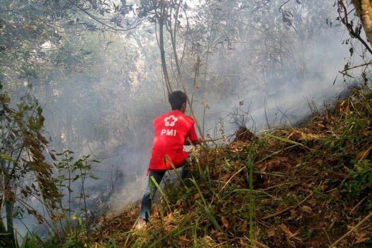 Relawan PMI mencoba memadamkan api yang membakar lahan hutan lereng utara Gunung Merbabu di Kecamatan Ampel, Kabupaten Boyolali, Jawa Tengah, Jumat (12/10/2018).