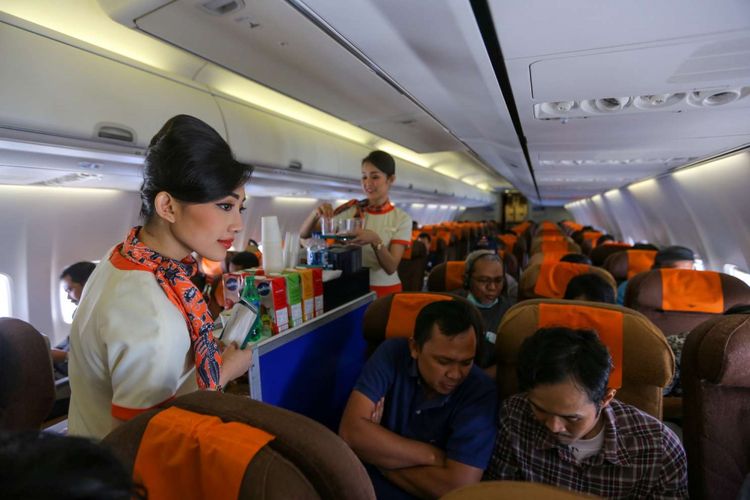 Awak kabin Garuda Indonesia, melayani penumpang pesawat dalam penerbangan Jakarta-Balikpapan, Jumat (7/12/2018). Garuda Indonesia meluncurkan layanan penerbangan bernuansa klasik bertajuk Garuda Indonesia Vintage Flight Experience dari tanggal 7-17 Desember 2018