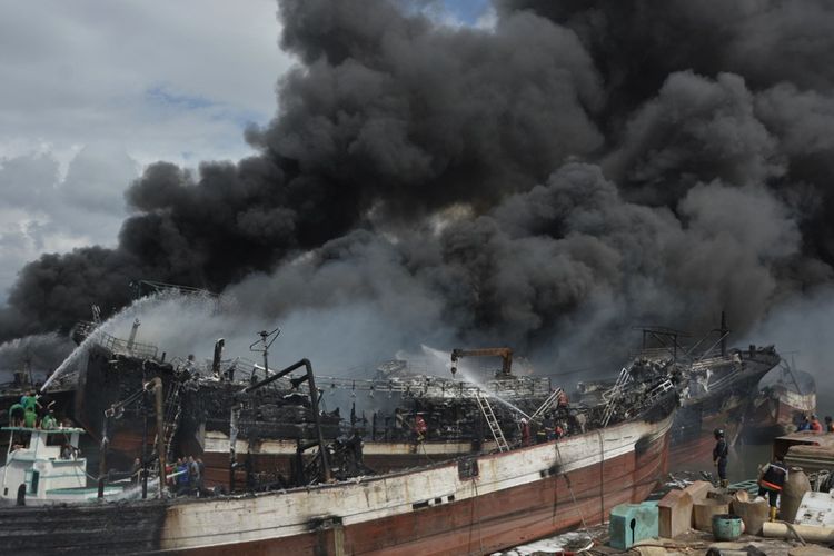 Petugas pemadam kebakaran dan warga berusaha memadamkan api yang membakar kapal ikan di Pelabuhan Benoa, Denpasar, Bali, Senin (9/7). Sekitar 39 unit kapal ikan terbakar dalam peristiwa kebakaran yang terjadi sejak pukul 02.00 Wita tersebut. 