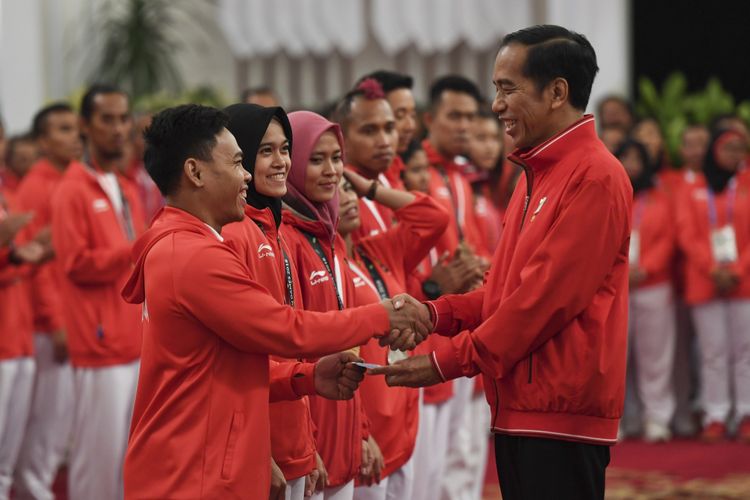 Presiden Joko Widodo (kanan) menyalami dan memberikan buku tabungan kepada lifter Eko Yuli Irawan (kiri) saat pemberian bonus kepada atlet peraih medali di Istana Negara, Jakarta, Minggu (2/9/2018). Pemerintah memberikan bonus kepada para atlet yang berhasil meraih medali dalam ajang Asian Games 2018. 