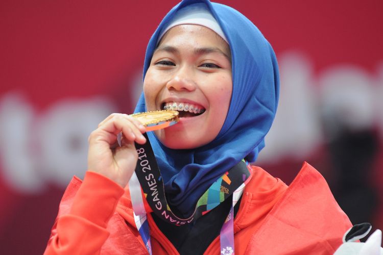 Taekwondoin putri Indonesia, Defia Rosmaniar menggigit medali emas yang diraihnya atas kemenangan di poomsae tunggal putri pertandingan Taekwondo di Asian Games 2018, di Jakarta Convention Center (JCC), Minggu (19/8). ANTARA FOTO/INASGOC/Sunyoto/inp/18