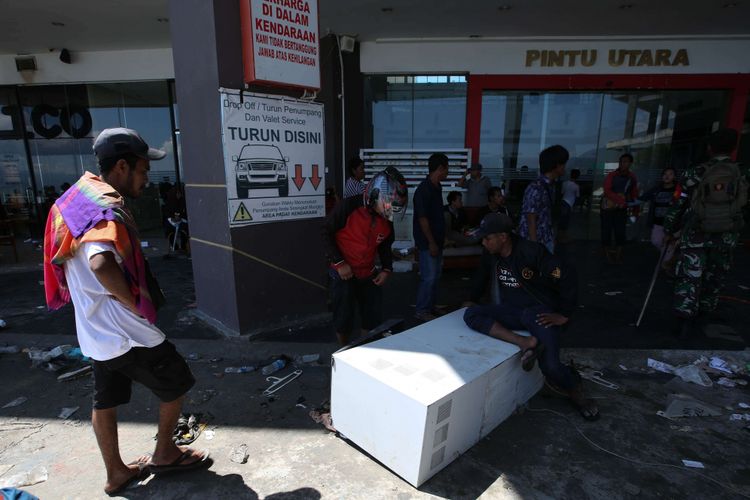 Warga menjarah barang di Grand Palu Mall usai gempa bumi di Pura, Kota Palu, Sulawesi Tengah, Minggu (30/9/2018). Gempa bermagnitudo 7,4 yang mengguncang Donggala dan Palu mengakibatkan ribuan bangunan rusak dan sedikitnya 420 orang meninggal dunia.(KOMPAS.COM/KRISTIANTO PURNOMO)