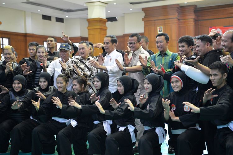 Presiden Joko Widodo (tengah) didampingi Menteri PUPR Basuki Hadimuljono (kelima kiri), Menpora Imam Nahrawi (keempat kanan) dan Ketua Harian Pengurus Besar Ikatan Pencak Silat Indonesia (IPSI) Edhy Prabowo (kelima kanan) berpose dengan atlet dan ofisial pelatnas pencak silat di Padepokan Pencak Silat TMII, Jakarta, Senin (6/8/2018). Presiden optimistis atlet pencak silat akan memperoleh lebih dari dua medali emas pada ajang Asian Games 2018.