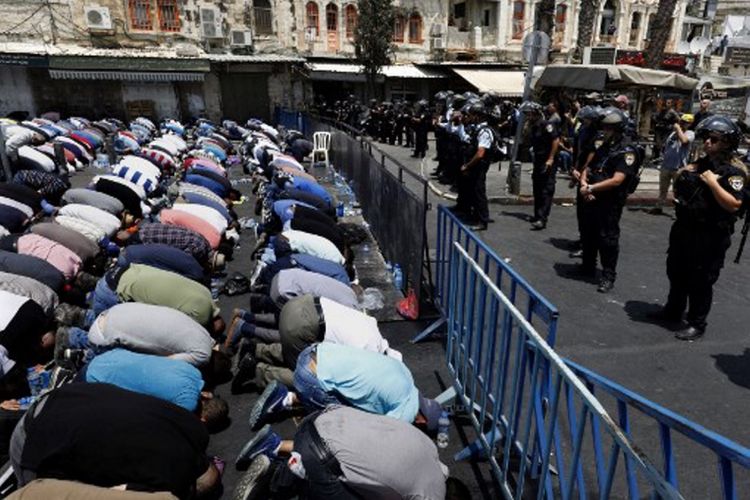 Warga Palestina menjalani ibadah Shalat Jumat di luar pintu masuk menuju kawasan Kota Tua Yerusalem di depan Masjid Al-Aqsa, Jumat (21/7/2017).  Israel melarang pria Palestina yang berusia di bawah 50 tahun untuk masuk ke kawasan Kota Tua dan menjalani Shalat Jumat, menyusul insiden penembakan dua polisi Israel.