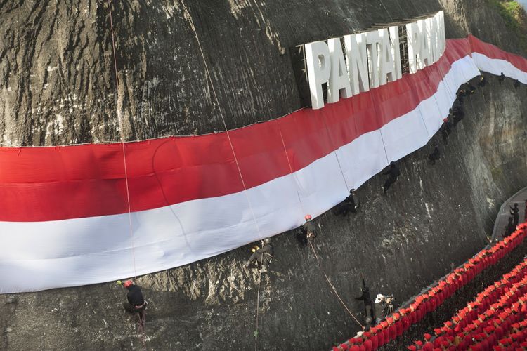 Anggota Brimob Polda Bali dan Basarnas mengibarkan Bendera Merah Putih di dinding tebing Pantai Pandawa, Badung, Bali, Senin (14/8/2017). Pengibaran Bendera Merah Putih sepanjang 800 meter tersebut untuk memperingati HUT ke-72 Proklamasi Kemerdekaan Indonesia, memperkuat nasionalisme dan sekaligus memecahkan rekor MURI. ANTARA FOTO/Nyoman Budhiana/pd/17.