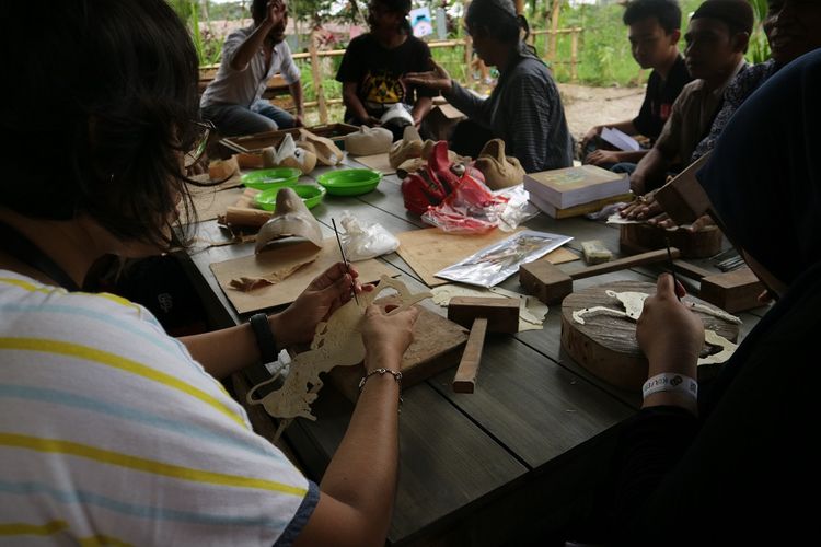 Peserta workshop mengikuti arahan dari maestro pembuatan wayang kulit, Saigo,tentang cara membuat wayang kulit di area workshop Kulon Progo Festival di Bendung Khayangan, DI Yogyakarta, Sabtu (25/11/2017).