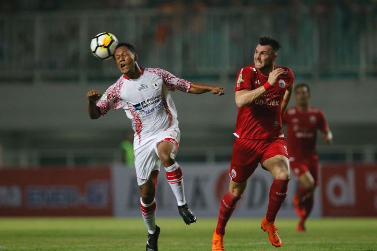 Yohanis Tjoe mencoba menghalau bola yang mengarah ke Marko Simic pada pertandingan Liga 1 antara Persija Jakarta dan Persipura Jayapura di Stadion Pakansari, 25 Mei 2018.