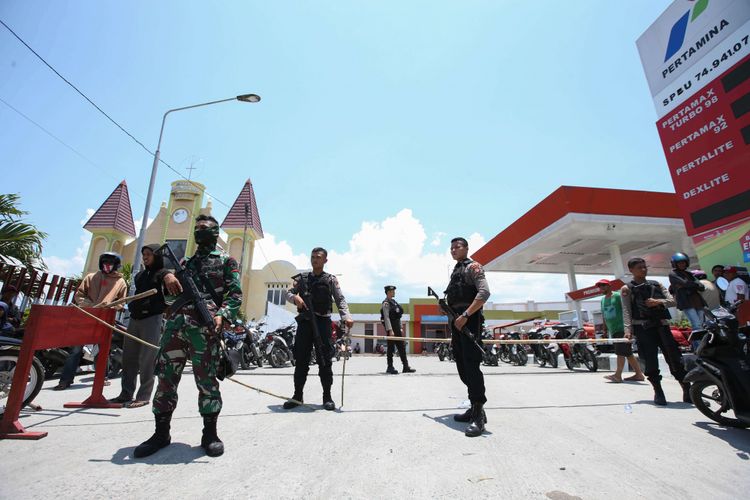 Polisi dan tentara menjaga warga yang antre membeli bahan bakar minyak di salah satu SPBU di Kota Palu, Sulawesi Tengah, pasca gempa dan tsunami, Rabu (3/10/2018). Hingga Hari ini pasokan BBM dari Pertamina di Palu berangsur normal.
