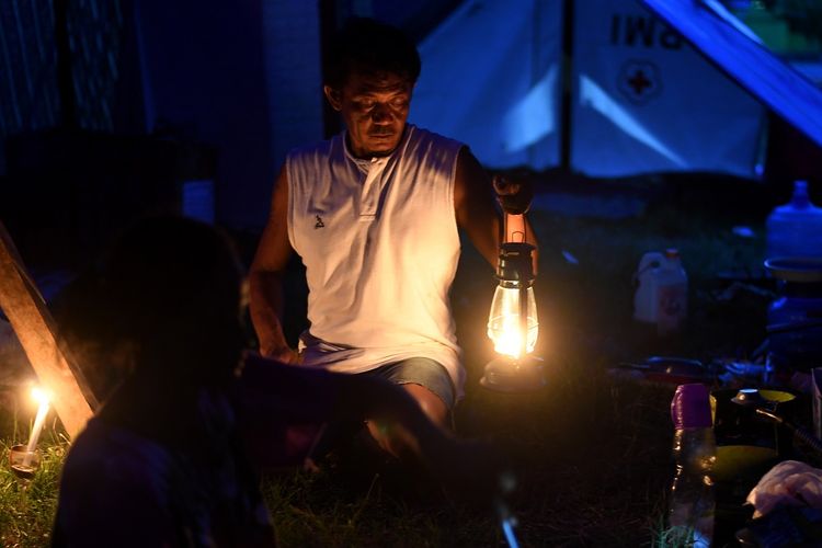 Warga membawa lampu petromaks untuk penerangan di tenda pengungsian kawasan Palu Barat, Senin (8/10). Berdasarkan data BNPB mengungsi akibat gempa dan tsunami Palu sebanyak 74.444 warga di 147 titik lokasi pengungsian.