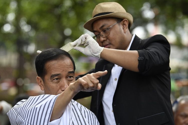 Presiden Joko Widodo (kiri) mengikuti potong rambut massal di area wisata Situ Bagendit, Garut, Jawa Barat, Sabtu (19/1/2019). ANTARA FOTO/Puspa Perwitasari/foc.