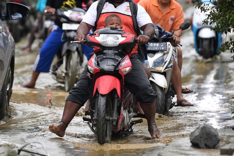 Warga berusaha menerobos endapan lumpur yang merendam jalan di Sentani pasca banjir bandang melanda wilayah tersebut, Sentani, Jaya Pura, Papua, Senin (18/3/2019). Akibat banjir bandang yang melanda Sentani sejak Sabtu (16/3) lalu, sedikitnya empat ribu warga mengungsi di sejumlah posko pengungsian. ANTARA FOTO/Zabur Karuru/foc.