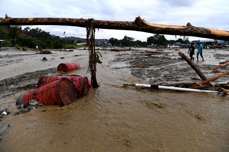 Warga melintasi endapan lumpur pasca banjir bandang melanda wilayah Sentani, Jaya Pura, Papua, Senin (18/3/2019). Akibat banjir bandang yang melanda Sentani sejak Sabtu (16/3) lalu, sedikitnya empat ribu warga mengungsi di sejumlah posko pengungsian. ANTARA FOTO/Zabur Karuru/foc.
