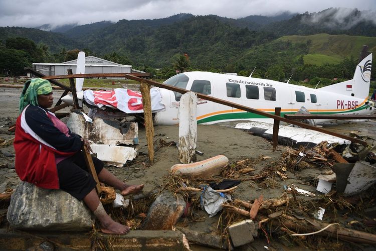 Warga mengamati sebuah pesawat yang terseret banjir bandang di Sentani, Jaya Pura, Papua, Senin (18/3/2019). Akibat banjir bandang yang melanda Sentani sejak Sabtu (16/3) lalu, sedikitnya empat ribu warga mengungsi di sejumlah posko pengungsian. ANTARA FOTO/Zabur Karuru/foc.