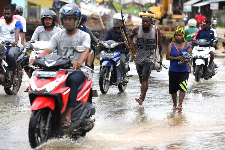 Warga dengan peralatan berburu melintasi genangan air pasca banjir bandang melanda wilayah Sentani, Jaya Pura, Papua, Senin (18/3/2019). Akibat banjir bandang yang melanda Sentani sejak Sabtu (16/3) lalu, sedikitnya empat ribu warga mengungsi di sejumlah posko pengungsian. ANTARA FOTO/Zabur Karuru/foc.