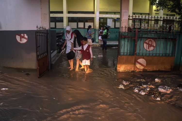 Warga melintasi genangan banjir bandang di SDN 224, Sukup Baru, Ujungberung, Bandung, Jawa Barat, Senin (1/4/2019). Banjir tersebut terjadi karena meluapnya Kali Cicalobak saat intensitas curah hujan yang tinggi yang merusak tanggul sehingga merendam sejumlah pemukiman warga serta merusak sebuah sebuah sekolah dasar. ANTARA FOTO/Novrian Arbi/foc.