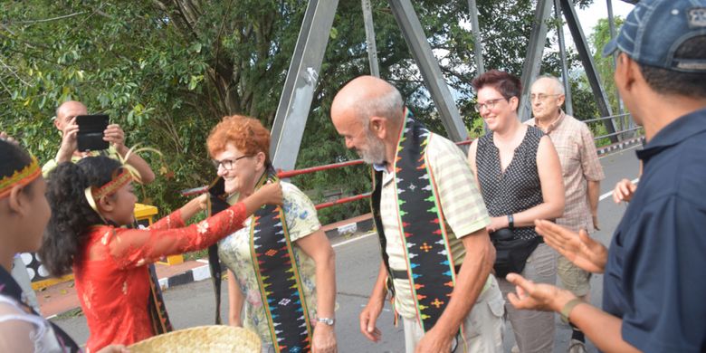 Seorang siswi SMPK Waemokel mengalungkan tamu Italia dan Jerman dengan selendang Songke di Jembatan Waemokel, Kabupaten Manggarai Timur, NTT, Rabu (15/8/2018).